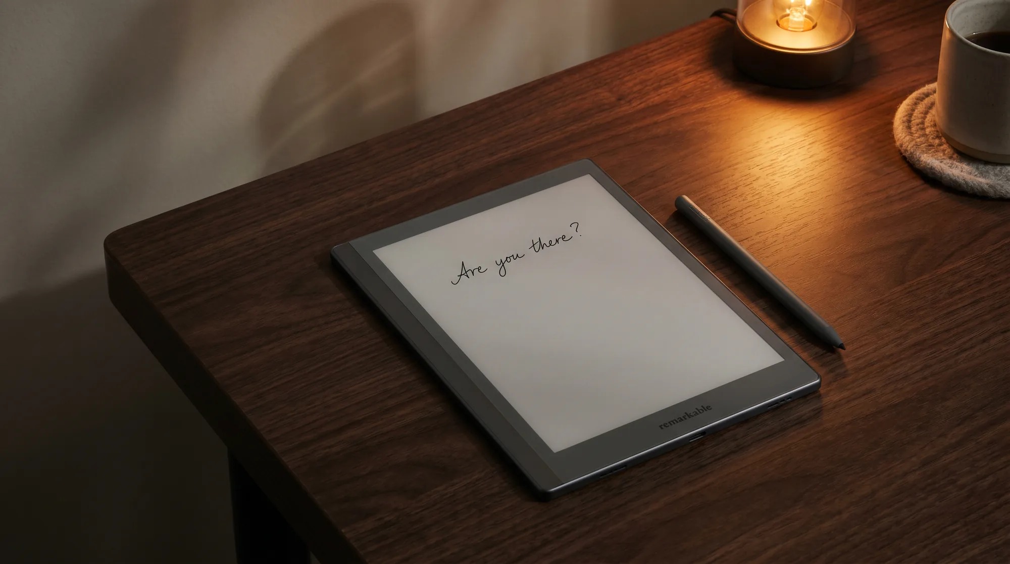 An e-ink writing tablet on a dark desk showing a short handwritten line, like Tom Riddle's diary