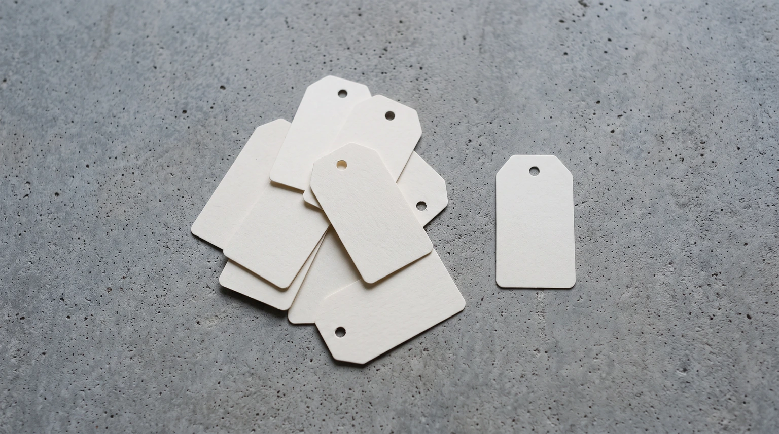 Overlapping blank price tags on a concrete surface with one set apart