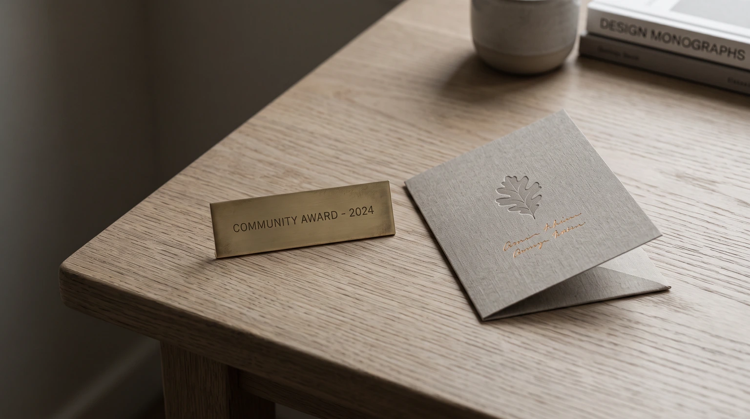 A small brass plate and a folded card on a wooden desk