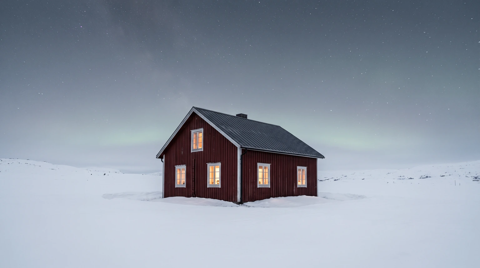 A single dark red Scandinavian cabin standing alone in deep fresh snow at night under a clear starry sky