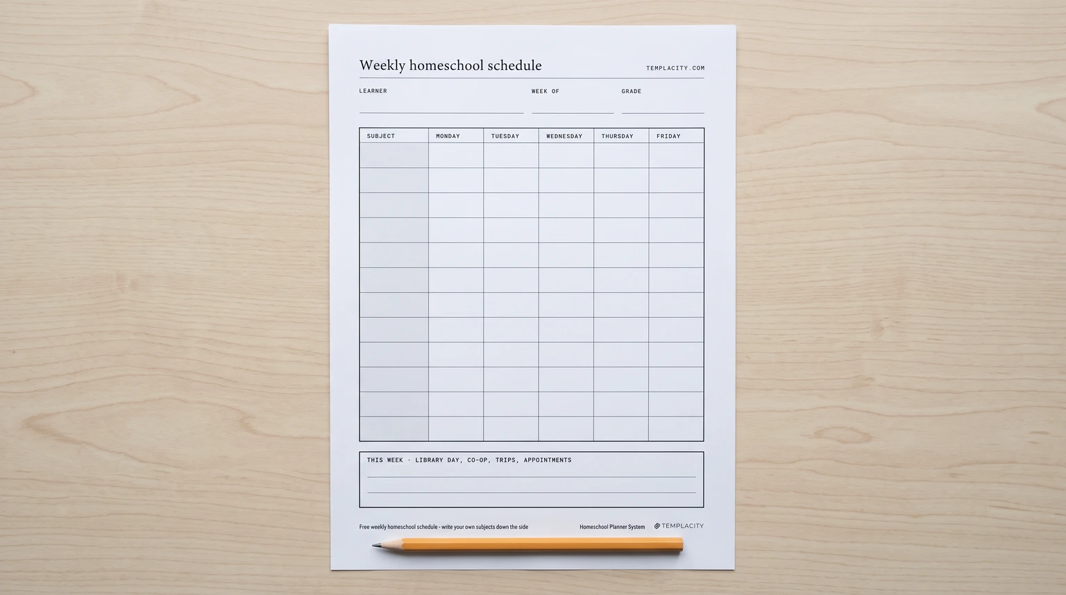 Our free weekly homeschool schedule printed on a pale wooden table with a pencil