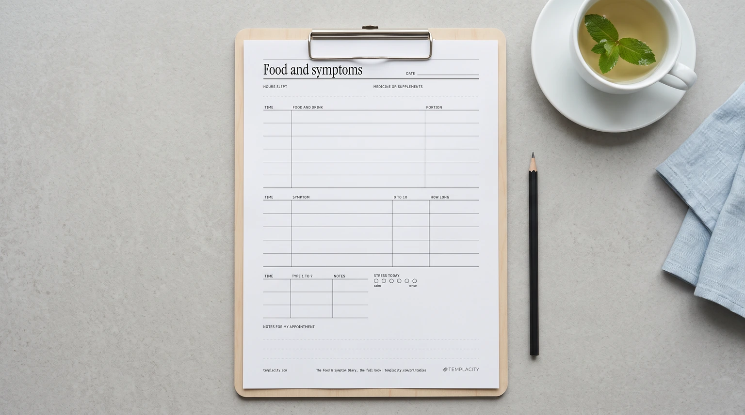 Our free IBS food diary page, with food, symptom and stool type columns, on a clipboard beside peppermint tea